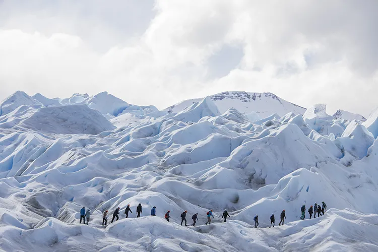 Grupo de aventureros con grampones realizando la excursión Minitrekking sobre la superficie azulada del Glaciar Perito Moreno en El Calafate.