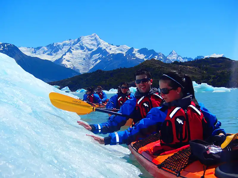 Remadores en kayak frente a los picos de hielo del Glaciar Perito Moreno, perspectiva de escala y silencio en el Canal de los Témpanos.