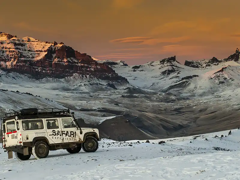 Camioneta 4x4 en el Cerro Comisión al atardecer, paisaje nevado y luces de puesta de sol durante el Safari Experience.