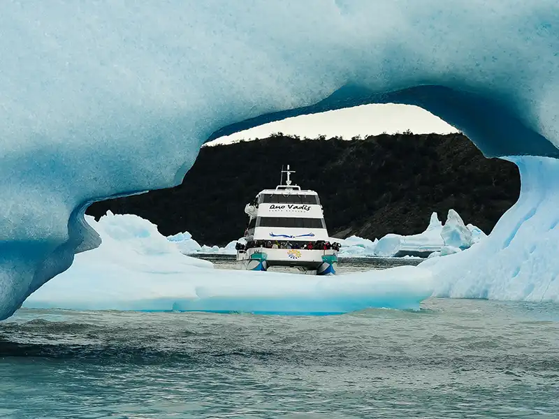 Catamarán navegando entre grandes témpanos de hielo azul en el Lago Argentino, aproximación al Glaciar Upsala en el brazo Norte.